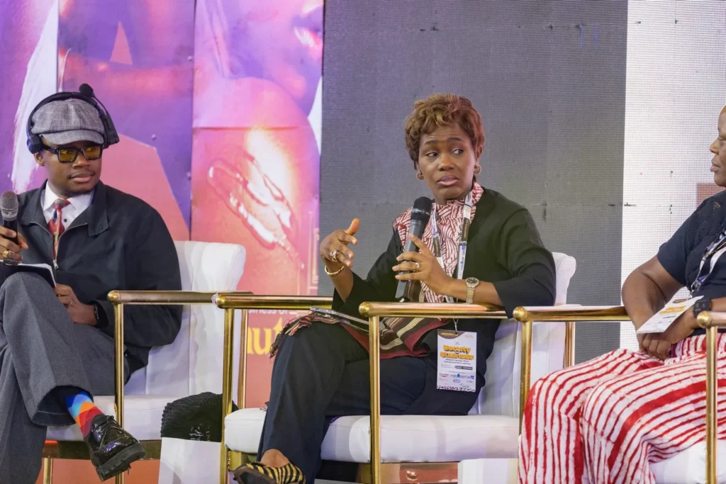Skinovation panel discussion with woman speaking and two seated panelists on stage.